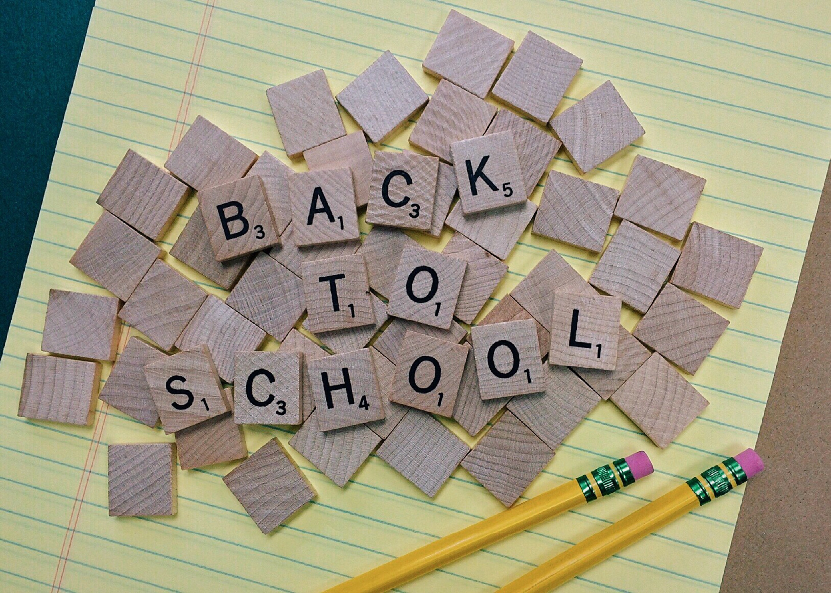 yellow note pad with pencils on it and scrabble letters "back to school"