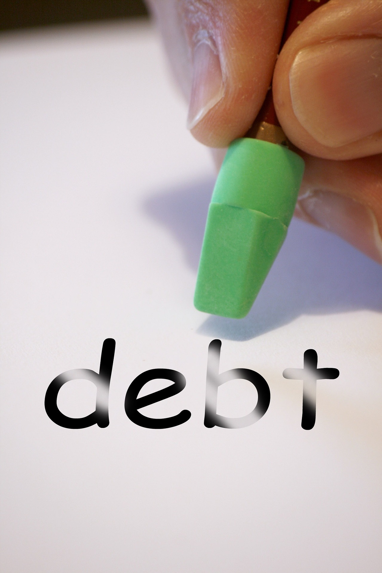 the word "debt" with a green eraser being held by a hand