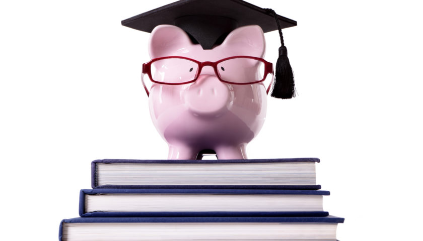 Pink piggy bank dressed as a college graduate or professor with mortar board and glasses standing on a small stack of books. Isolated on white. Designed by Freepik