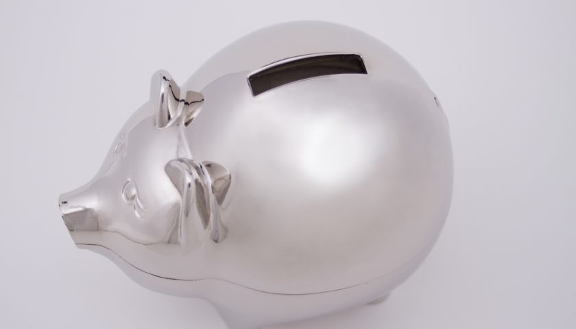 A silver piggy bank from the top view with a large black slit on the top for coins and a plain