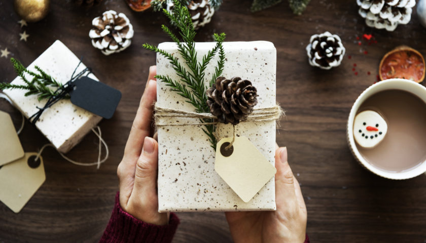 gift being presented that is wrapped in twine with pine branch and pine cone