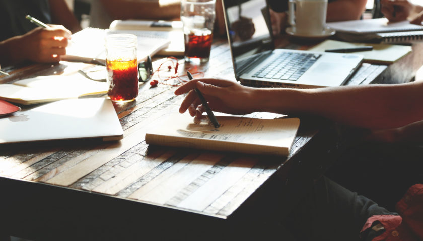 table with study material around it and people sitting around with pen and paper