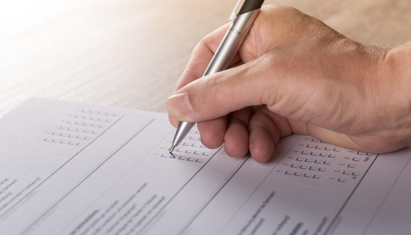 Hand holding a pen completing a survey