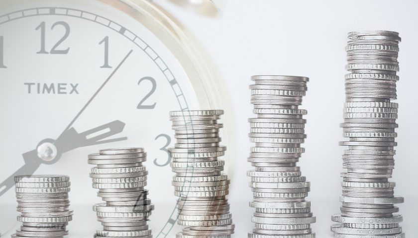 Stack of coins with timex clock in background