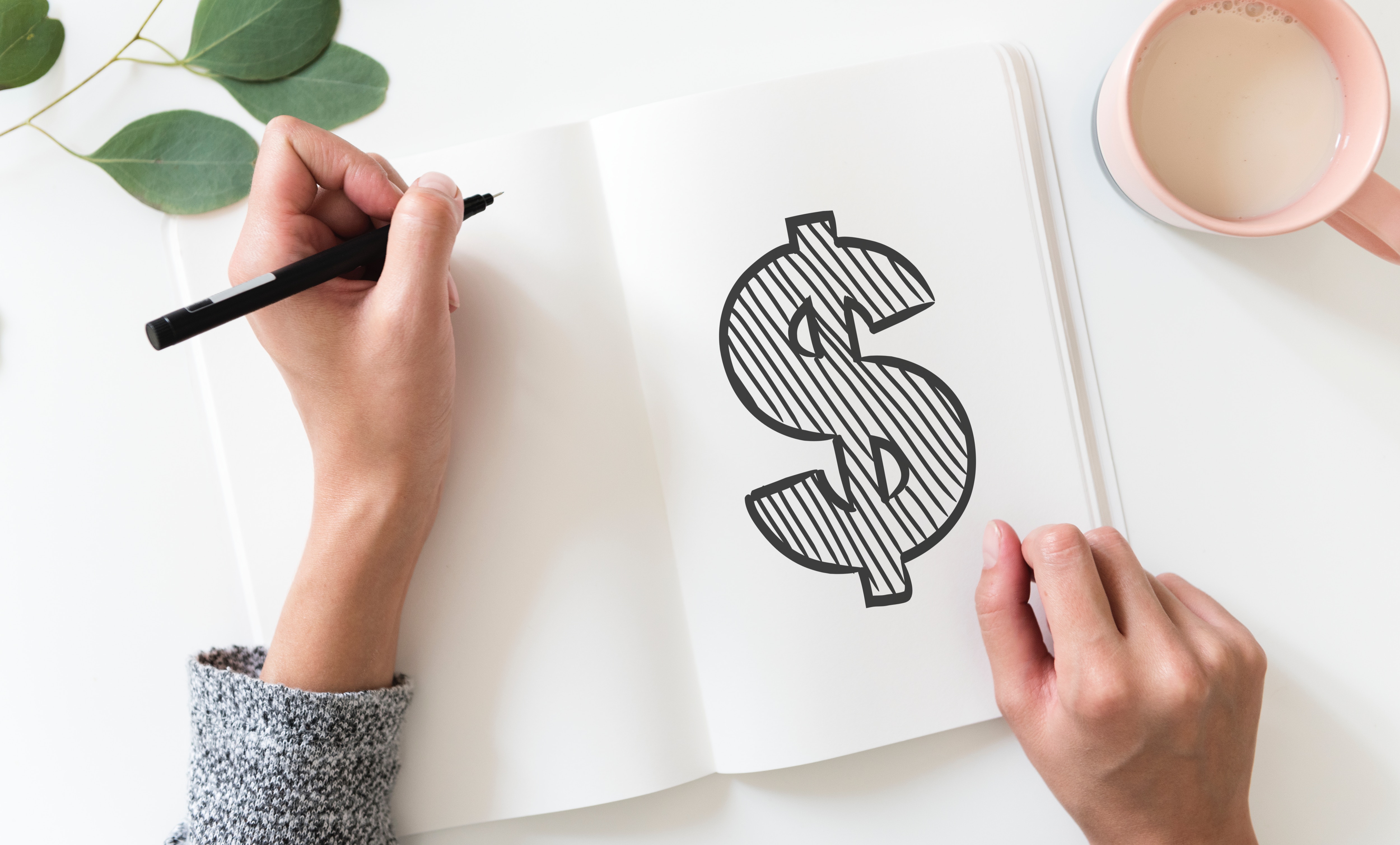person with pen in hand drawing a dollar sign Photo by rawpixel on Unsplash