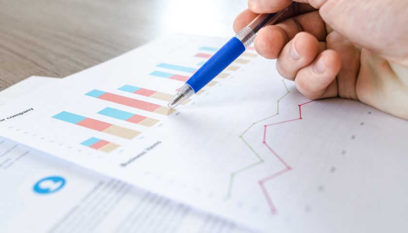 hand holding a pen pointing at charts