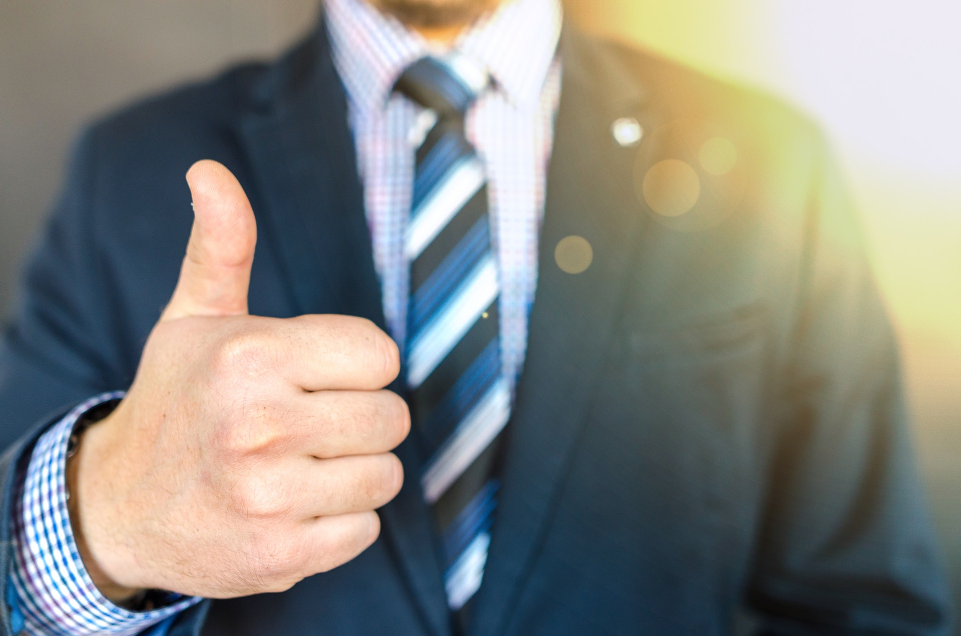 focus on thumbs up with background of person in suit blurry