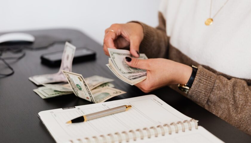 crop payroll clerk counting money while sitting at table