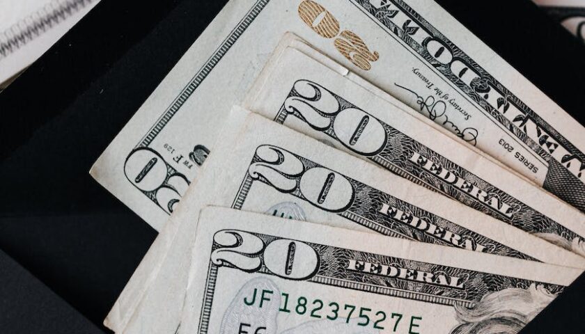 stack of dollars and black envelope with banknotes inside