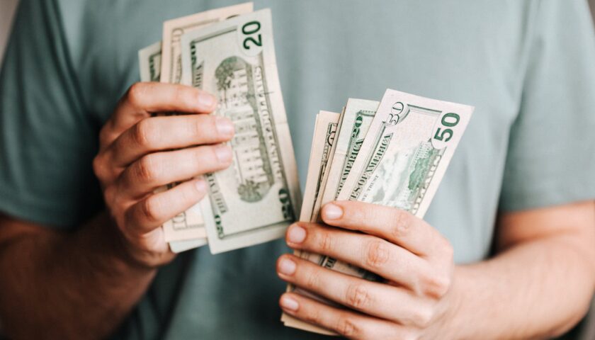 crop man counting dollar banknotes